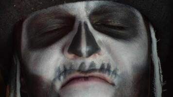 Close-up man face in skeleton Halloween cosplay removing hands from face and looking wide open eyes video