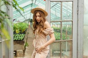 A beautiful young woman takes care of plants in a greenhouse. The concept of gardening and an eco-friendly lifestyle. photo