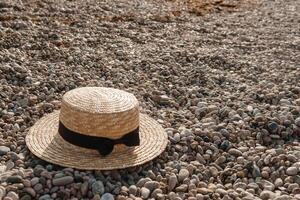 A straw hat on the beach. Pebbles on the seashore, close-up. The natural background. photo