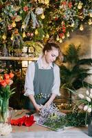 A woman in her florist shop collects bouquets of flowers. The concept of a small business. Bouquets of tulips for the holiday on March 8. photo