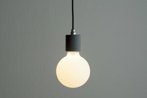 Single Lit Bulb on Grey Background photo