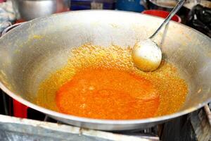 Cocinando tailandés curry comida . verter el Coco Leche dentro el dorado naranja curry en el pan foto