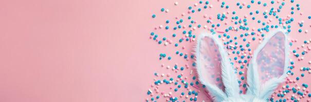 top view of adorable bunny ears and a sprinkle of confetti on a pastel blue backdrop photo