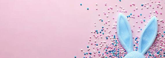 top view of adorable bunny ears and a sprinkle of confetti on a pastel blue backdrop photo