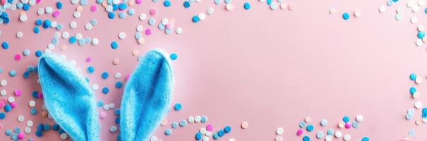 top view of adorable bunny ears and a sprinkle of confetti on a pastel blue backdrop photo