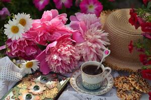 Beautiful still life with peony flowers, vintage cup and cookies on the table. Romantic greeting card for birthday, Valentines, Mothers Day concept. Summer background with vintage objects photo