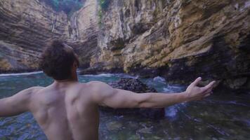 The free man raises his arms looking at the cliffs in the sea. video