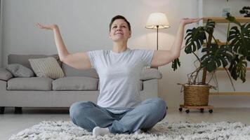senior vrouw aan het doen meditatie oefening uitrekken sport- yoga. helder kamer Bij huis video