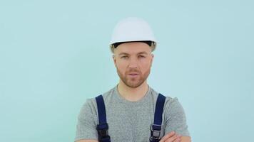 Serviceman in a helmett and overalls looking at camera on blue background video