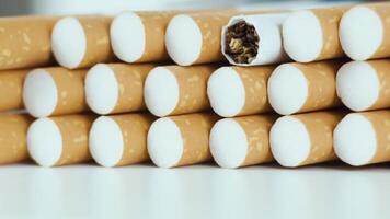 hoop van tabak sigaretten draait Aan een wit achtergrond dichtbij omhoog video