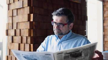 volwassen mannetje leest de druk op terwijl zittend in een cafe. de gepensioneerde is resting video