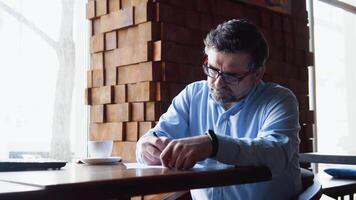 Sénior homme panneaux les documents séance dans une café video