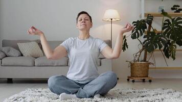 anziano donna fare meditazione esercizio allungamento gli sport yoga. maturo salutare donna allenarsi a casa, esercizio, in forma, fare yoga, casa fitness concetto video