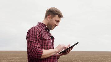 Farmer on a field with a tablet before planting agricultural cultures video