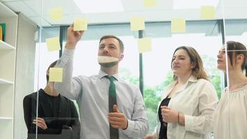 jovem corporação empregados estão discutindo uma o negócio plano com adesivos dentro a escritório video