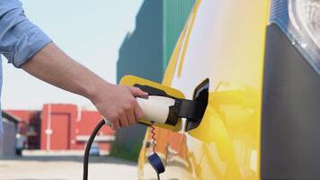 Unrecognizable man unplugs charging cable electric vehicle. Male hand disconnects power connector into EV car video