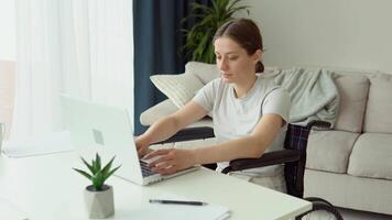 Motivated freelancer is working typing in laptop sitting in wheelchair at home. Distant work concept video