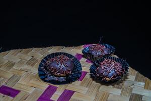 Isolated chocolate dumplings, close-up view of chocolate dumplings sprinkled with sprinkles, with woven bamboo as a base. Eid meal concept. photo