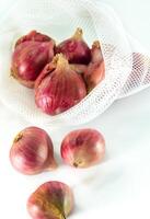 Red onions in mesh bag isolated on white background photo