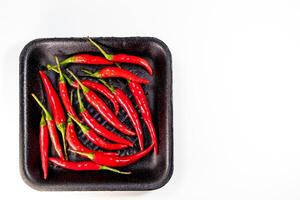 Red chili in black foam tray isolated photo