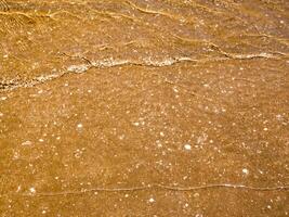 Light reflection on surface of movement sea on sand beach photo