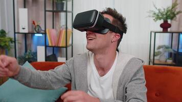 jong Mens gebruik virtueel realiteit koptelefoon bril Bij huis Speel 3d spel maken gebaren met handen video