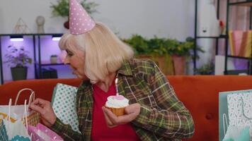 contento mayor mayor abuela mujer celebrando cumpleaños fiesta, hace deseo soplo ardiente vela video