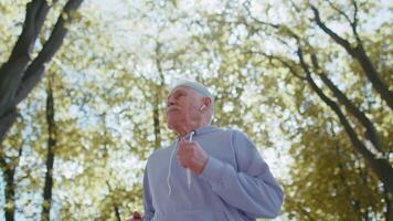 gemotiveerd atletisch geschiktheid gepensioneerd senior oud Mens rennen in park, opa gezond actief sport video