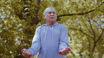 Senior homem exercício, fazer haltere peso elevação exercícios, praticando Esportes Treinamento dentro parque video