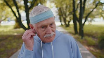 Portrait of athletic senior sport runner man wearing earphones listening music, smiling, cardio video