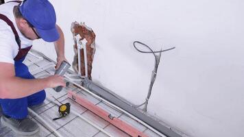 man worker takes measurements during the installation of a warm floor. Warm floor heating system video