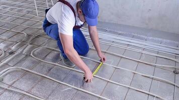 uomo lavoratore prende misurazioni durante il installazione di un' caldo pavimento. caldo pavimento riscaldamento sistema. video