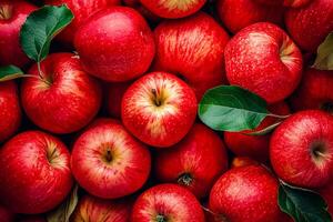 Bunch of red apples are piled together with some having leaves on them photo