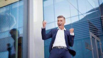 negocio, empresario celebrando éxito emocionado caucásico masculino negocio persona ganar en línea casino lleno de alegría sensación eufórico recepción agradable mensaje teléfono inteligente caminando al aire libre bailando contento video