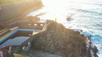 aérien drone vue de robuste rocheux littoral avec vagues s'écraser et rupture contre rochers à lever du soleil. video