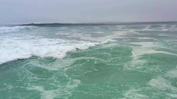 drone en volant faible plus de océan vagues rupture près rive. video