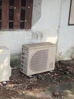 dirty air conditioner unit near cement wall photo