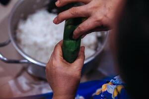 closeup of hands making lontong wrapped in banana leaves photo