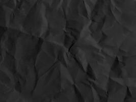 Black crumpled paper texture in low light background photo