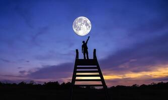 man standing on stairs hand touch on the moon abstract goals concept photo