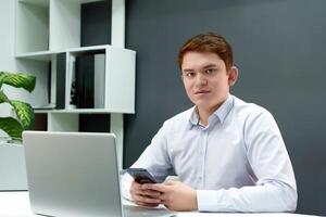 estratégico joven profesional conduce productivo negocio conversaciones terminado el teléfono mientras quedarse en el computadora en un elegante oficina ambiente foto