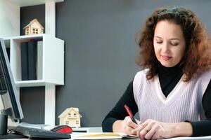 confident middle-aged girl with curly hair sits at her desk, writing neatly in a notebook, reflecting her organization and attention to detail photo