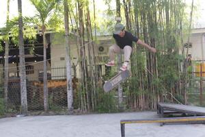 Indonesia - Medan 17 August 2023 an asian man doing skateboard tricks on a ramp photo