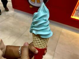 someone holding a large ice cream cone with blue icing photo