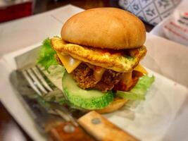 hamburger with egg, meat and vegetable filling on the table photo