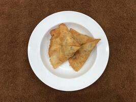 Fresh delicious crispy Two samosas on white Plate, top view, isolated photo