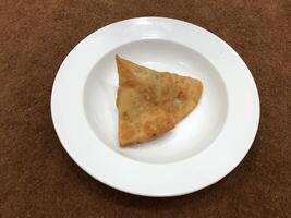 Fresh delicious crispy samosas on white Plate, top view, isolated photo