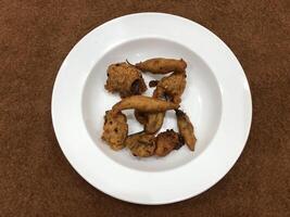 Mirchi pakora or Mirchi bhajji served in a white plate, a famous midday snack in india, served over a rustic wooden background, selective focus photo