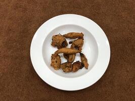 Mirchi pakora or Mirchi bhajji served in a white plate, a famous midday snack in india, served over a rustic wooden background, selective focus photo