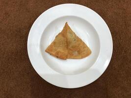 Fresh delicious crispy samosas on white Plate, top view, isolated photo